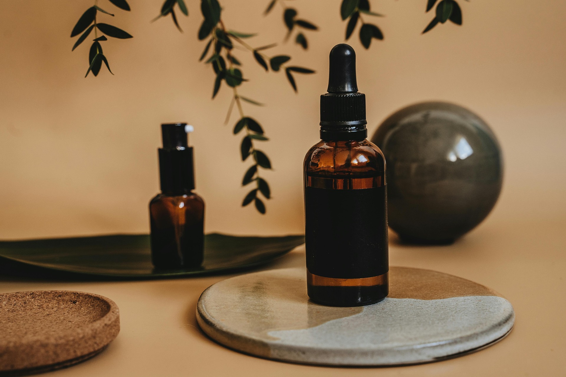 Amber glass skincare serum bottles with droppers displayed on a decorative stone tray with natural accents